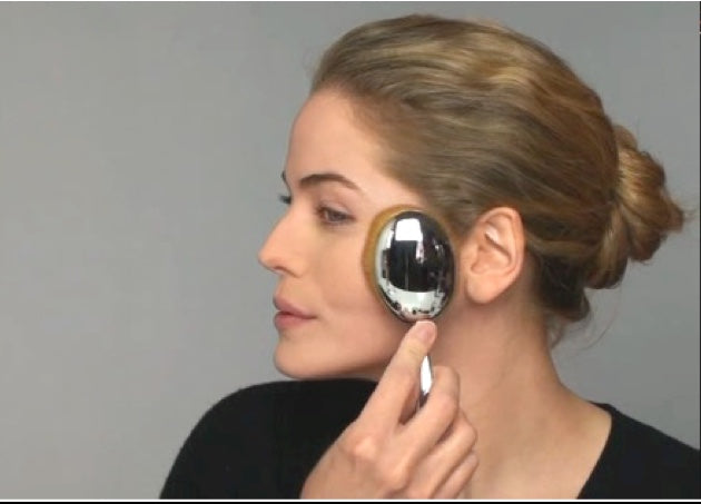 this is an image of a model using an Elite Oval 10 brush to apply setting powder to her face.