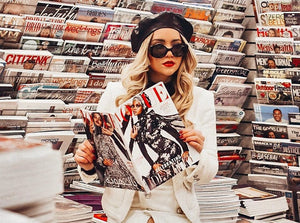 person perusing newsstand with fashion magazines