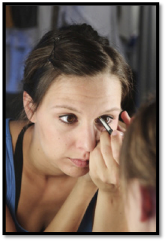 this is an image  of a woman trying to apply eye makeup using a conventional brush while looking into a mirror. A very awkward undertaking.